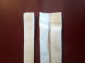 Zwei weiße Bänder liegen auf einem Tisch, eins ist der Länge nach mittig gefaltet