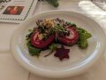 Salat und eine rote Roulade sind auf einem weißen Teller angerichtet
