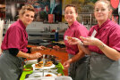 Drei Frauen in Kochkleidung bereiten verschiedene Kostproben auf Baguette vor