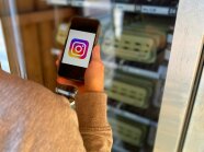 Man sieht ein Handy mit dem Instagram- Symbol vor einem Verkaufsautomaten im Hintergrund