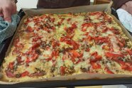 Ein Blech mit Blumenkohlpizza, belegt mit Pizzabelag wie Salami, Paprika und Käse.