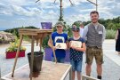 Ein Mitarbeiter des AELF mit einem  Mädchen und einem Jungen, den Siegern des Melkwettbewerbs