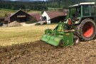 Traktor mit angehängter Fräse auf einem unbearbeitetem Feld