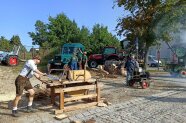 Ein Mann schneidet mit einer alten Kreissäge Holz, die von einem Standmotor betrieben wird.