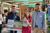 3 Personen stehen an Stand nebeneinander