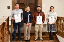 4 Personen stehen nebeneinander, 3 davon halten eine Urkunde